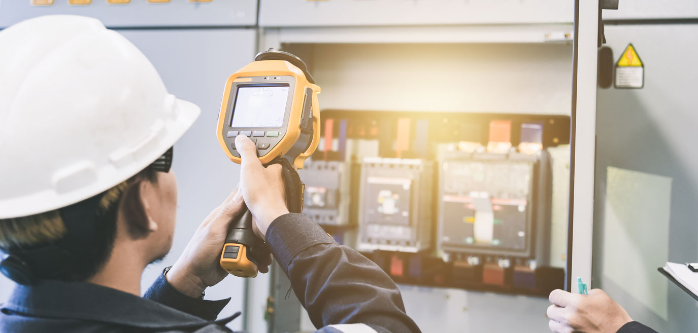 Professional using an instrument to assess an electrical utility vault.