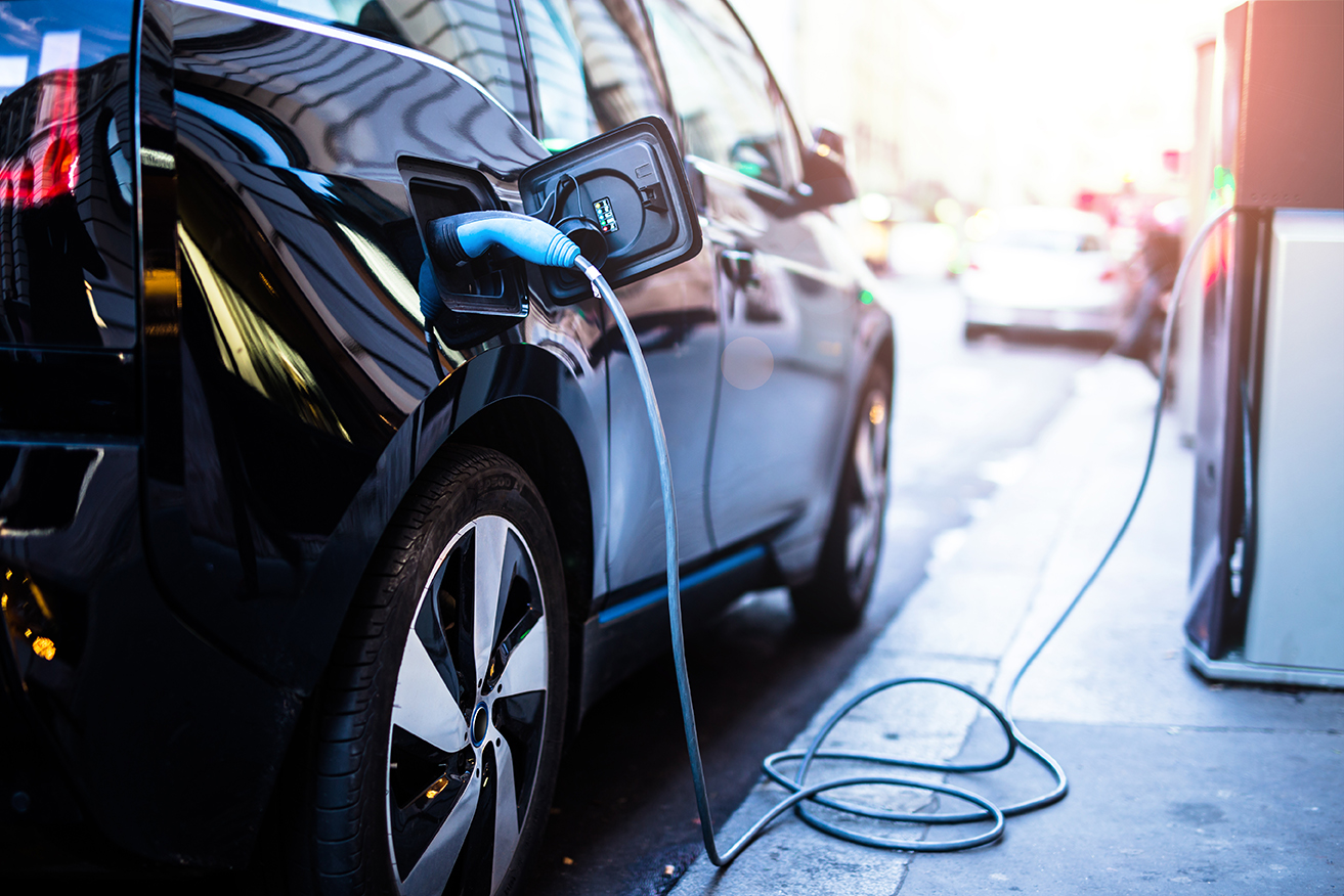 Electric vehicle parked and charging during sunset.